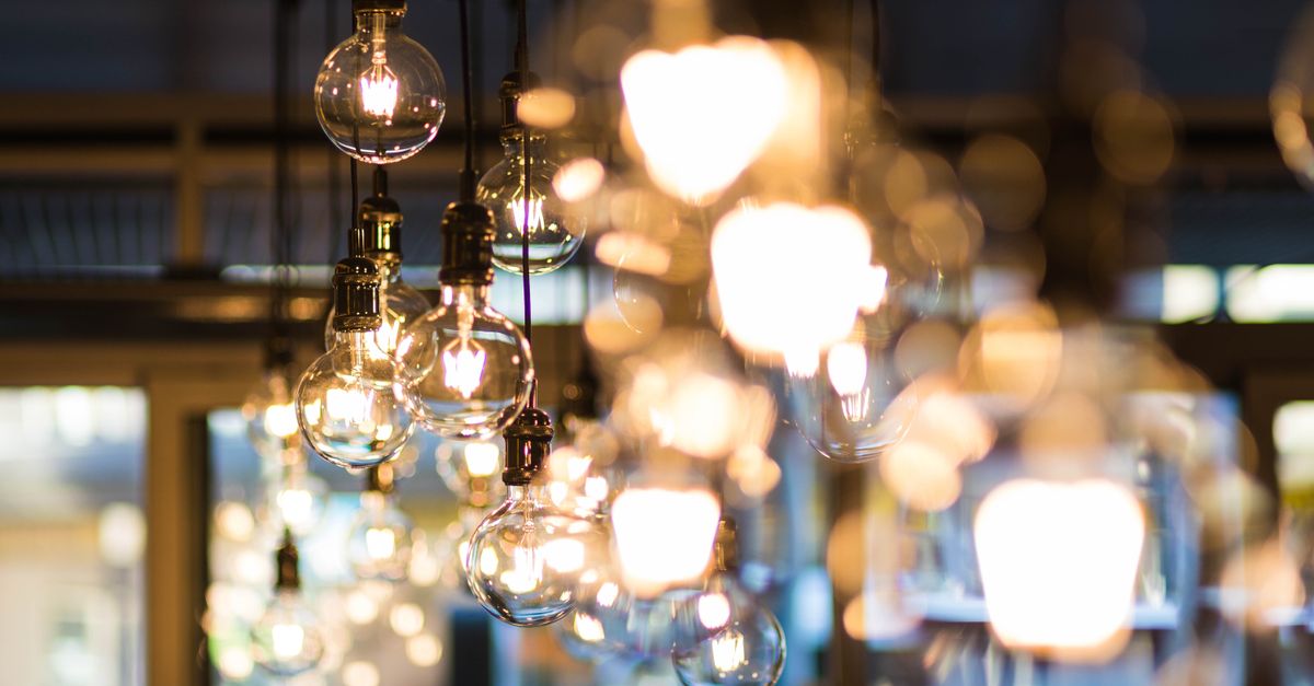 A modern and ambient urban setting with glowing, hanging light bulbs in focus.